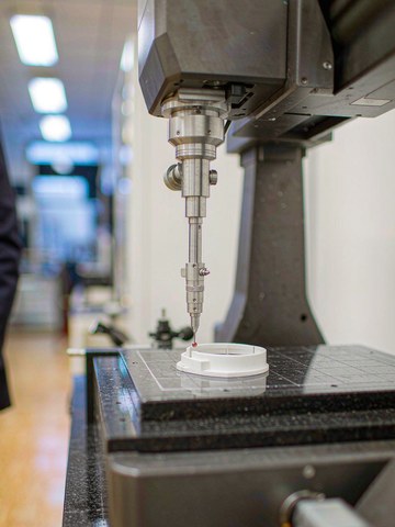 Zeiss CMM probe measuring a white PEEK ring on a granite table after temperature stabilization