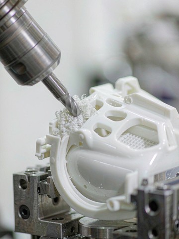 Machining a white PEI aerospace interior bracket on a small vertical CNC machining center