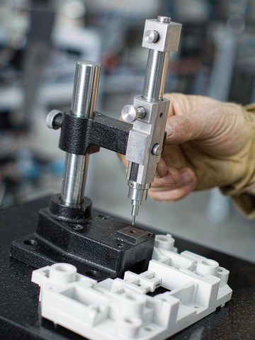 Quality inspection of machined white polymer aerospace parts with a digital height gauge on a granite surface plate