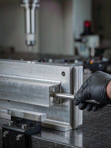 Hand checking the slip fit of a hardened dowel pin in a reamed bore of an aluminum frame plate