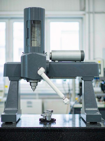 Inspector verifying a freshly machined aluminum prototype with a coordinate measuring machine