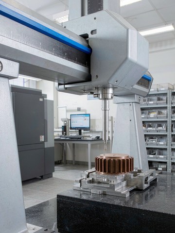 Quality inspector measuring a machined part on a bridge CMM in the inspection lab