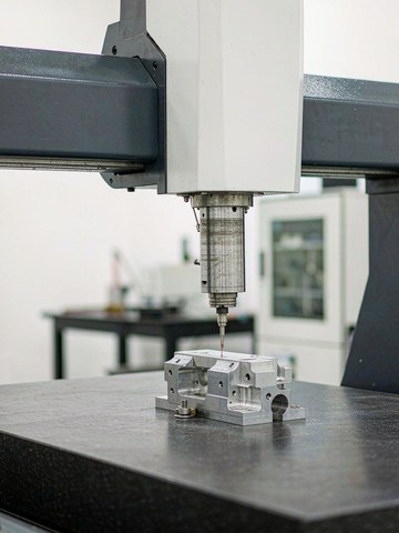 CMM inspection room at a CNC machining supplier: bridge CMM measuring an aluminum housing on a granite table