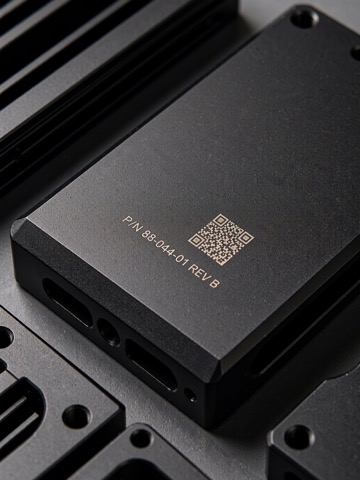 Close view of laser marked text and a readable Data Matrix code on a black anodized aluminum housing