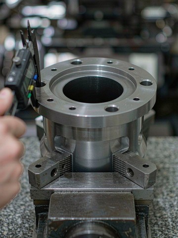 Digital caliper checking a machined Inconel 718 flanged part held in a precision vise