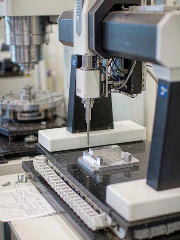 Bridge CMM first article inspection probing an aluminum machined part on a granite table