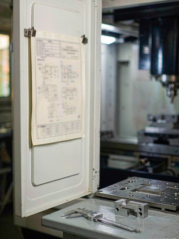 Controlled process card in a magnetic holder on a CNC machine, returned at shift change under NDA file control
