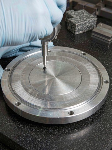 Dial indicator sweep across the sealing face of a machined aluminum vacuum chamber lid