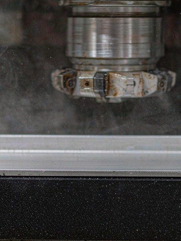 Thin aluminum plate held flat on a porous vacuum chuck during machining