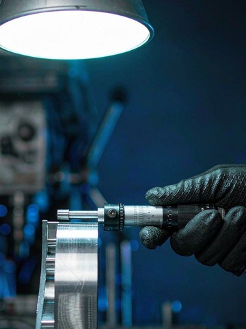 Micrometer check on a precision machined aluminum part finished from a cut blank