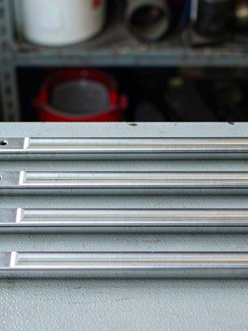 Machined hardened steel pivot pins and bushings arranged on a workbench