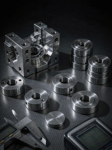 Finished titanium machined parts measured with a caliper on an inspection bench before CMM reporting
