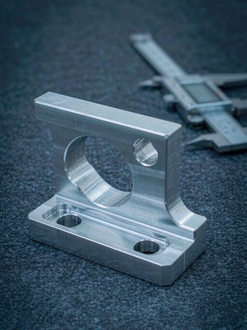 DFM friendly machined aluminum part with open pockets, generous corner radii and precision bores on a workbench.