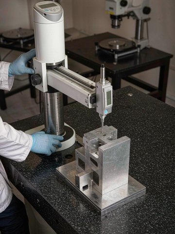 Inspector measuring datum surfaces of a machined plate with a digital height gauge on a granite surface plate for GD&T verification.