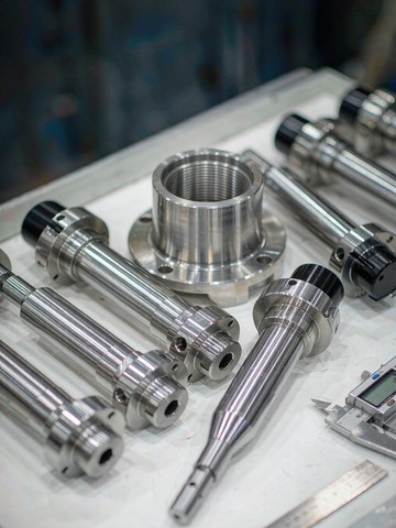 Finished steel shafts and sealing caps with low-Ra turned surfaces laid out for final inspection.