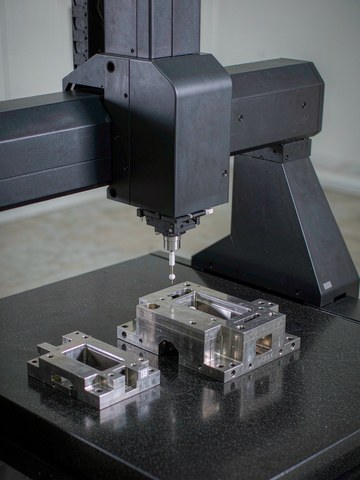 Bridge coordinate measuring machine verifying a precision stainless steel component on a granite table.